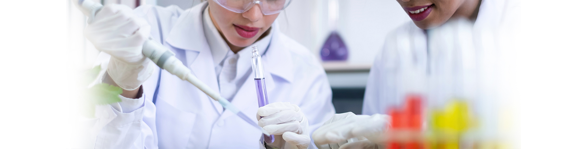 Imagem de dois cientistas fazendo testes e injetando substâncias em um frasco com um líquido roxo
